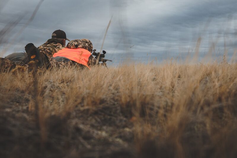 Jakt med Bipod Skjutstöd - 2 jägare som ligger på marken med ett gevär fäst i Bipod